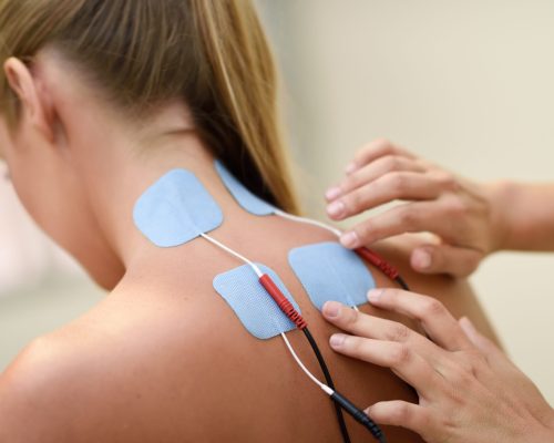 Electro stimulation in physical therapy to a young woman. Medical check at the shoulder in a physiotherapy center.